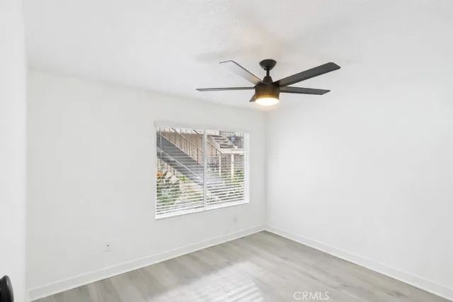 an empty room with ceiling fan and window