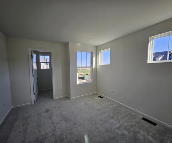 a view of an empty room with closet and windows