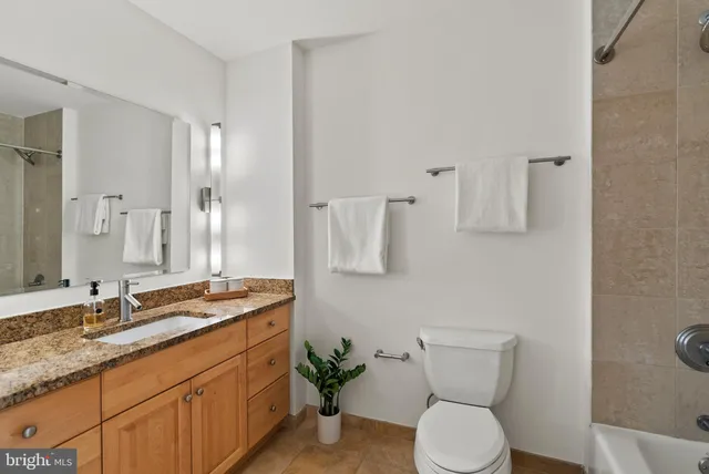 a bathroom with a granite countertop toilet sink and mirror