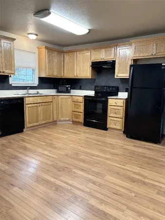 a kitchen with granite countertop a refrigerator stove top oven and sink