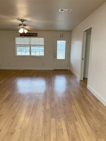 an empty room with wooden floor chandelier and windows