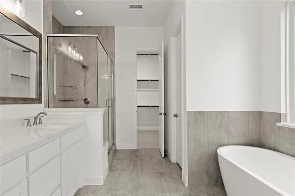 a bathroom with a tub shower sink and mirror