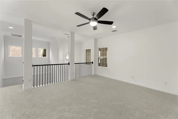 an empty room with ceiling fan and windows