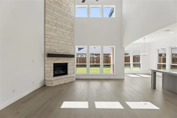 a view of an empty room with wooden floor and a fireplace