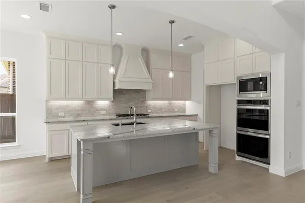 a kitchen with stainless steel appliances granite countertop a sink a stove and a refrigerator