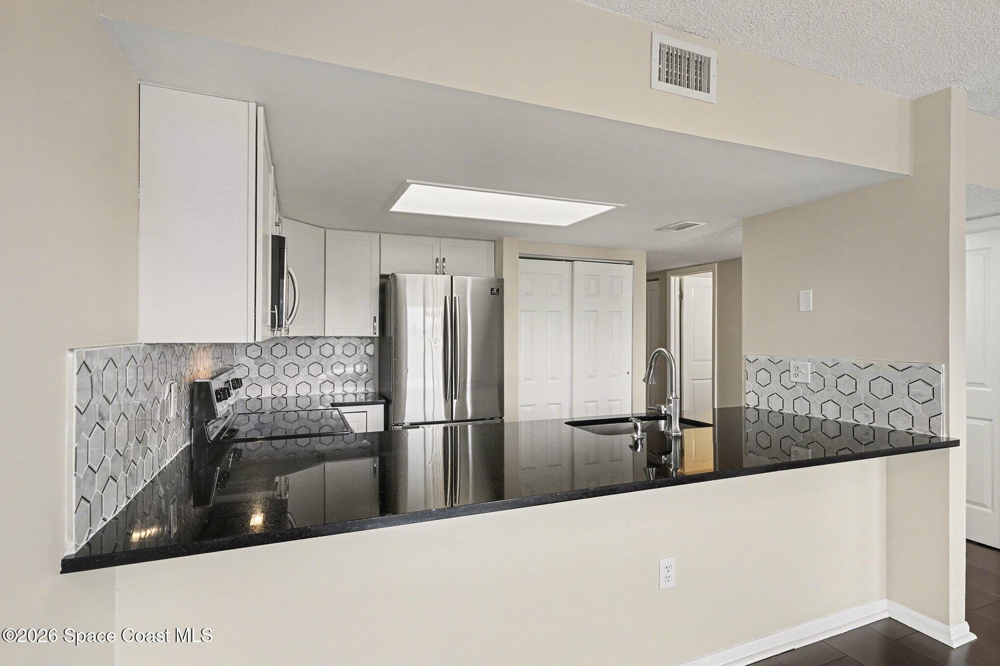 1011 Clearmont Street Northeast, Unit 1022 Palm Bay, FL 32905 - Photo 7 of 16 a kitchen with stainless steel appliances granite countertop a refrigerator and a sink