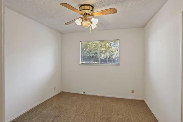 an empty room with a window and a chandelier fan