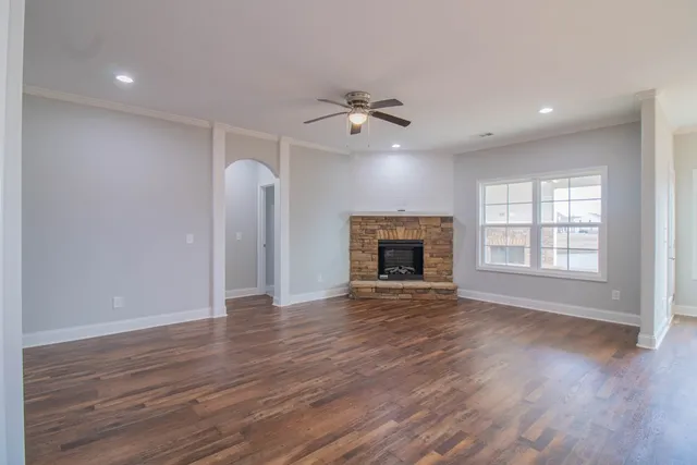 an empty room with wooden floor fireplace and a window
