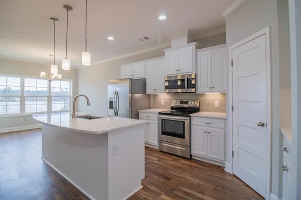 a kitchen with kitchen island granite countertop a sink stainless steel appliances and white cabinets