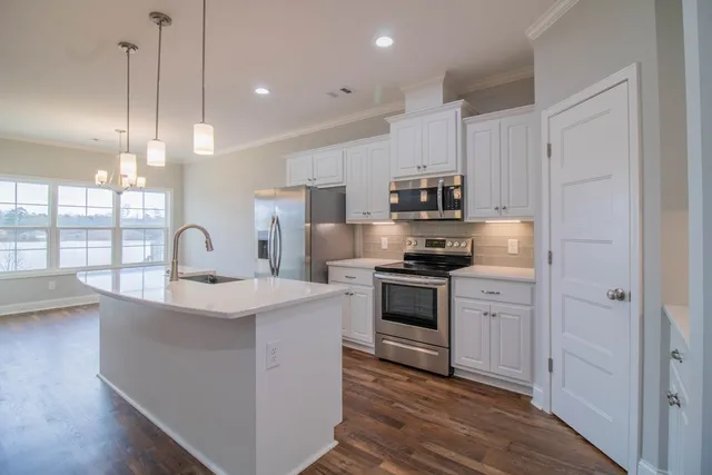 a kitchen with kitchen island granite countertop a sink stainless steel appliances and white cabinets