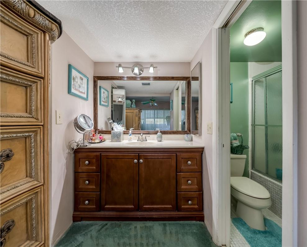 3955 North Nob Hill Road, Unit 408 Sunrise, FL 33351 - Photo 19 of 34 a bathroom with a granite countertop sink a toilet and a mirror