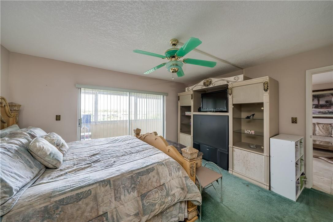 3955 North Nob Hill Road, Unit 408 Sunrise, FL 33351 - Photo 24 of 34 a bedroom with a bed and a ceiling fan