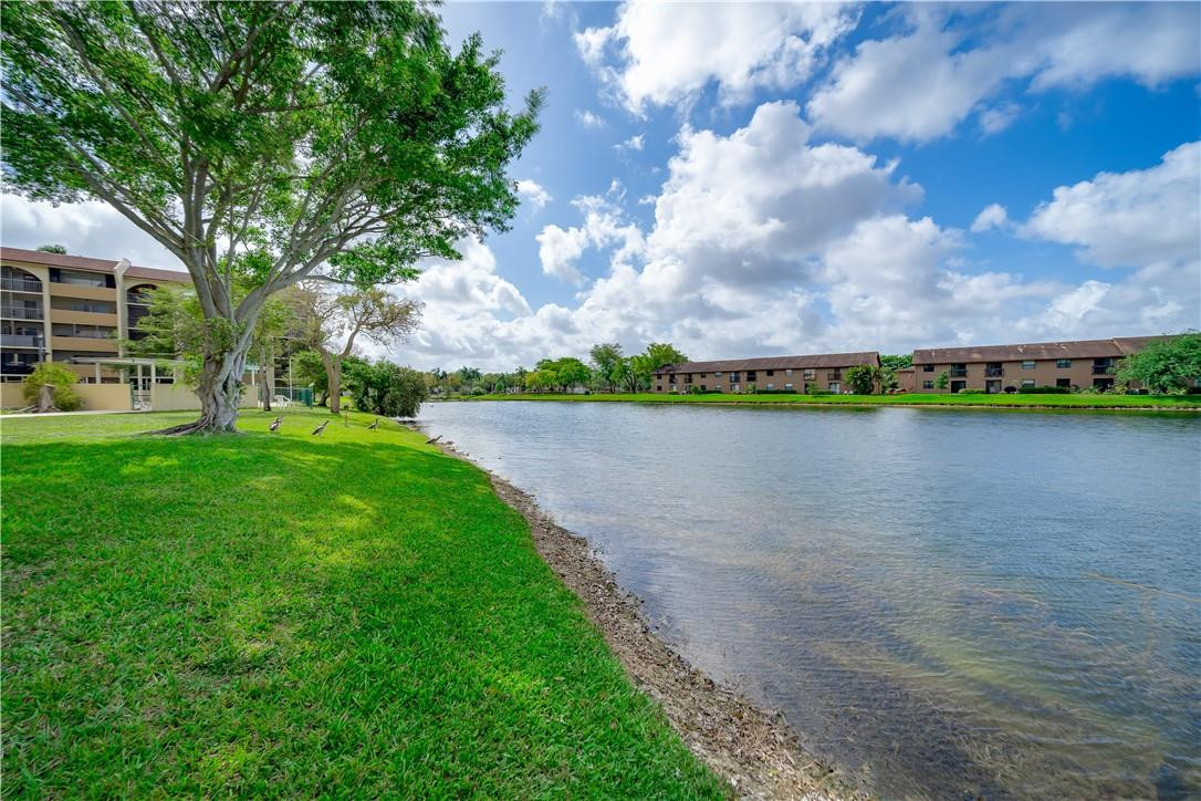 3955 North Nob Hill Road, Unit 408 Sunrise, FL 33351 - Photo 30 of 34 a view of a lake with a big yard and large trees