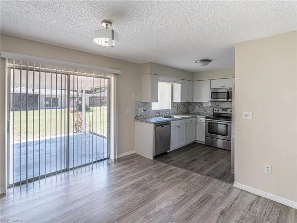 a kitchen with granite countertop wooden floors and white stainless steel appliances