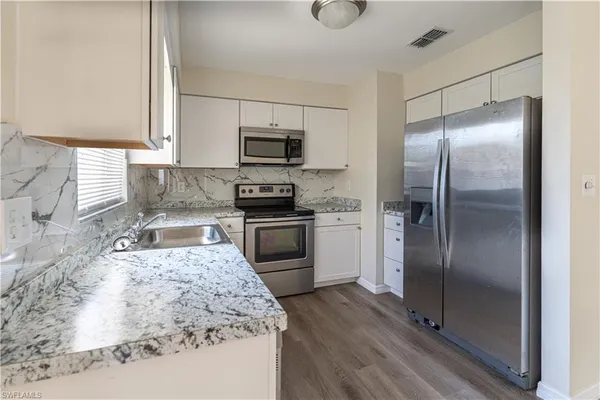 a kitchen with stainless steel appliances granite countertop a refrigerator a stove and a sink