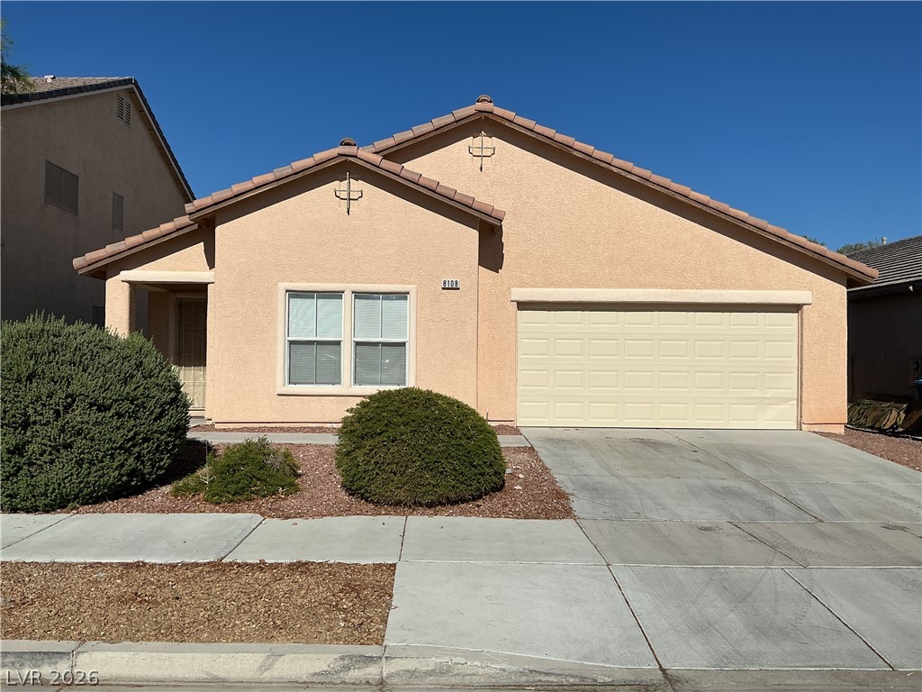 A well-maintained stucco home with a tile roof and attached garage awaits.