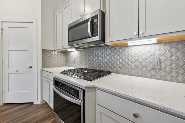 a kitchen with granite countertop cabinets stainless steel appliances and wooden floor
