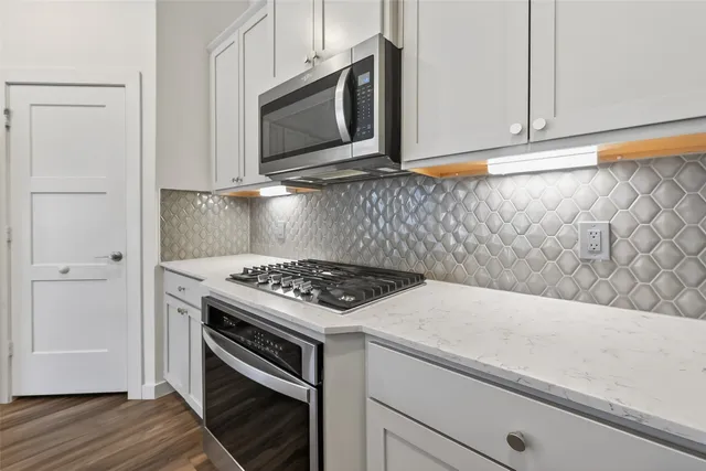 a kitchen with granite countertop cabinets stainless steel appliances and wooden floor