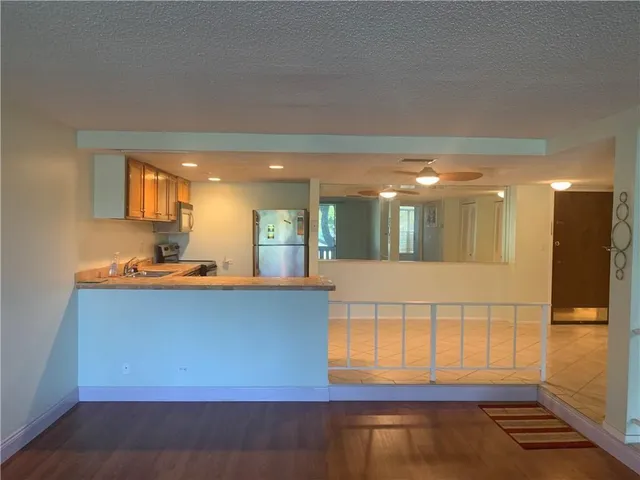 a view of a kitchen with kitchen island a sink wooden floor and a large window