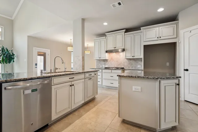 a kitchen with granite countertop a sink and white cabinets