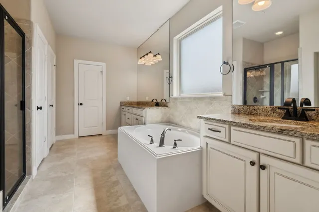 a bathroom with a sink double vanity granite tub shower and a mirror