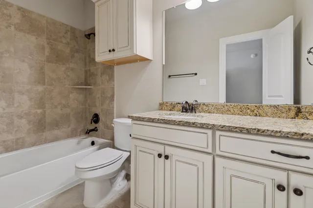 a bathroom with a granite countertop sink a toilet and bathtub