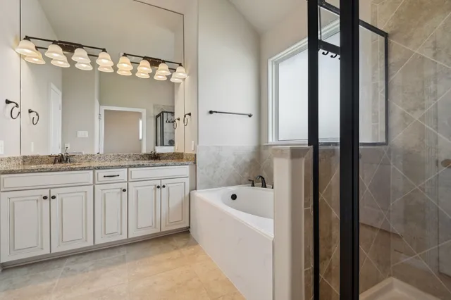 a spacious bathroom with a granite countertop sink mirror and a bathtub