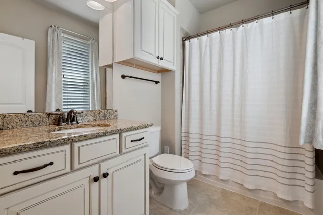 a bathroom with a granite countertop toilet sink and mirror