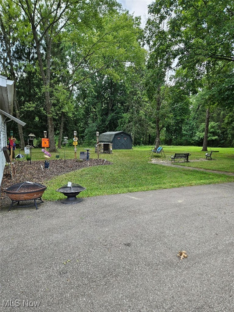View of home's backyard with a fire pit, a shed, and view of scattered trees