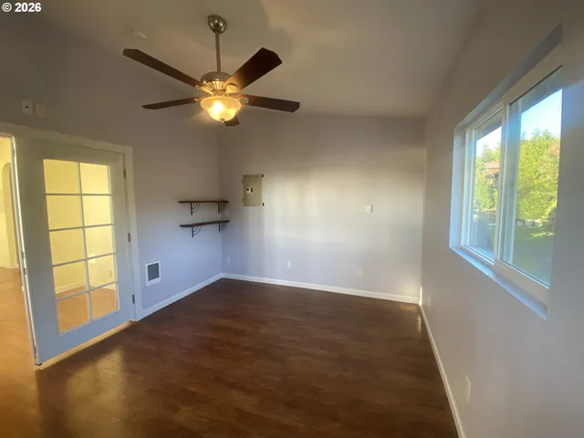 a view of empty room with wooden floor and fan