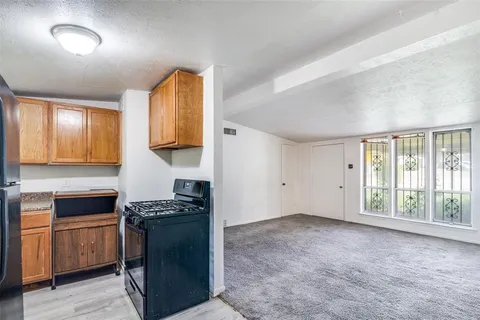 a kitchen with granite countertop a stove a sink and a refrigerator