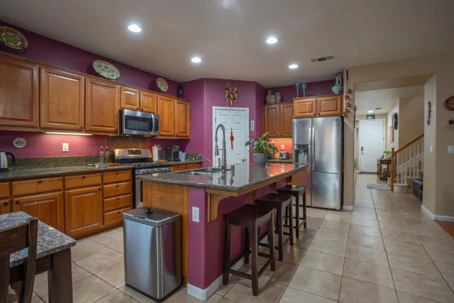 a kitchen with stainless steel appliances granite countertop a refrigerator a stove a sink a dining table and chairs