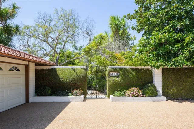 a backyard of a house with large trees and plants