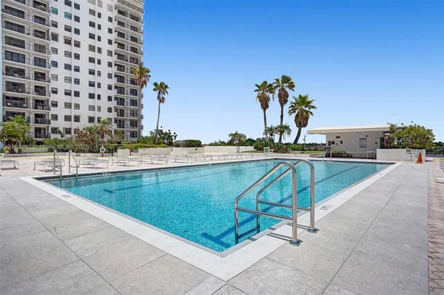 a view of a swimming pool with a lawn chairs under an umbrella