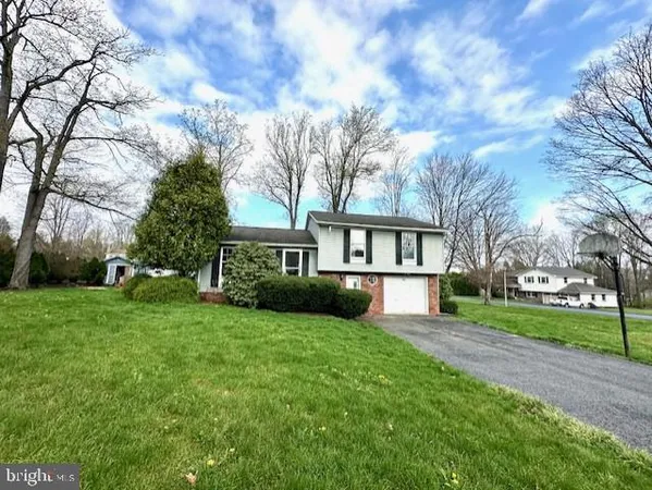 a view of house in front of a big yard with large trees