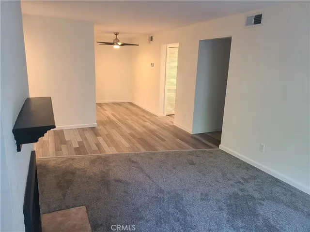 a view of an empty room with wooden floor and a fireplace