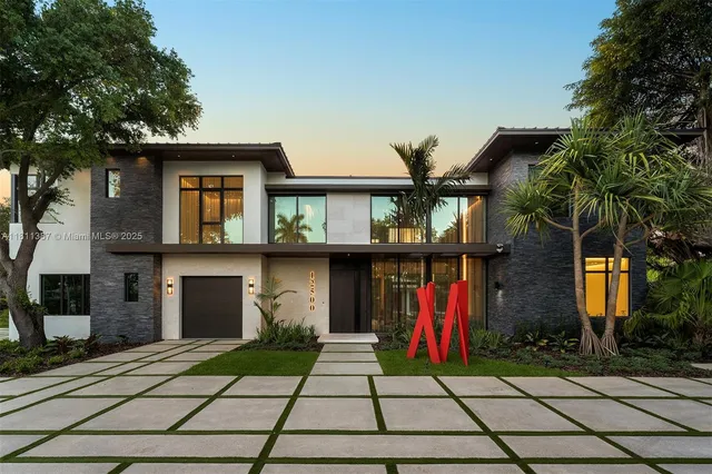 a front view of a house with lots of trees and plants