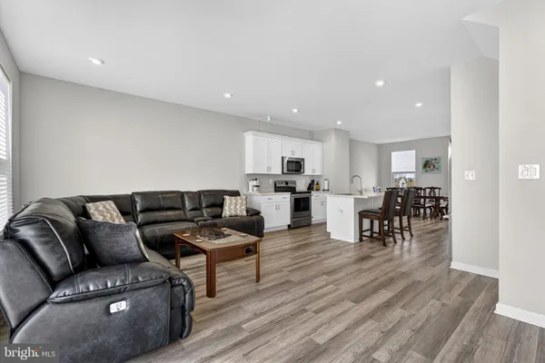 a white kitchen with wooden floor stainless steel appliances and white cabinets