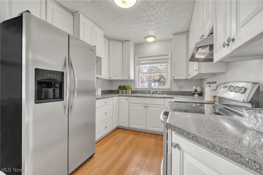 2440 White Road Cleveland, OH 44118 - Photo 28 of 43 Kitchen with light hardwood / wood-style flooring, sink, stainless steel appliances, white cabinets, and a textured ceiling