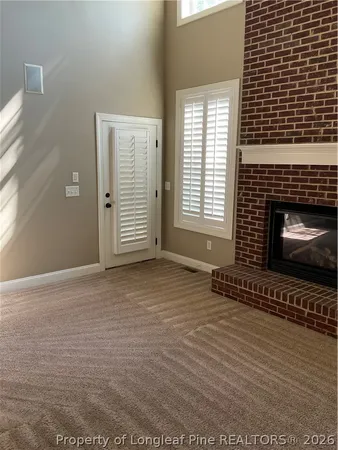 a view of an empty room with a fireplace and a window