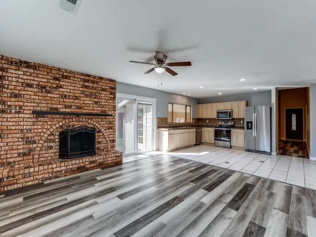 a living room with stainless steel appliances kitchen island granite countertop furniture and a fireplace