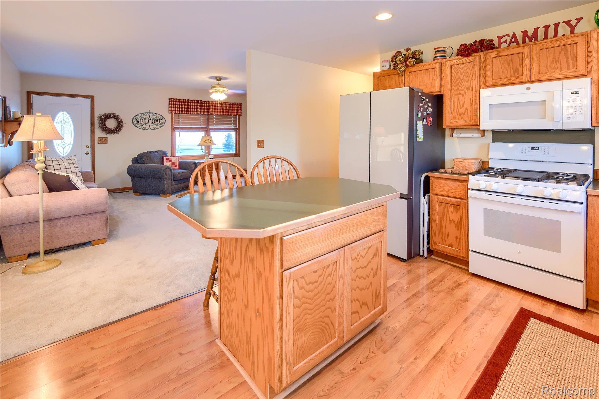 6941 North Lake Pleasant Road North Branch, MI 48461 - Photo 51 of 51 Kitchen with a kitchen bar, white appliances, open floor plan, a kitchen island, and light wood-style flooring