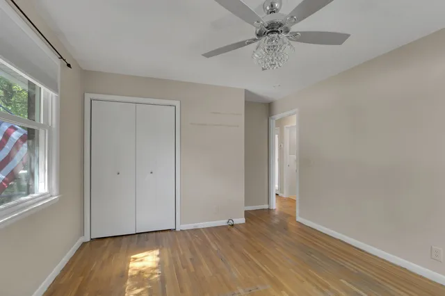 a view of an empty room with window and wooden floor