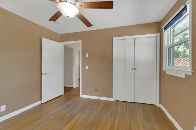 an empty room with wooden floor and a ceiling fan