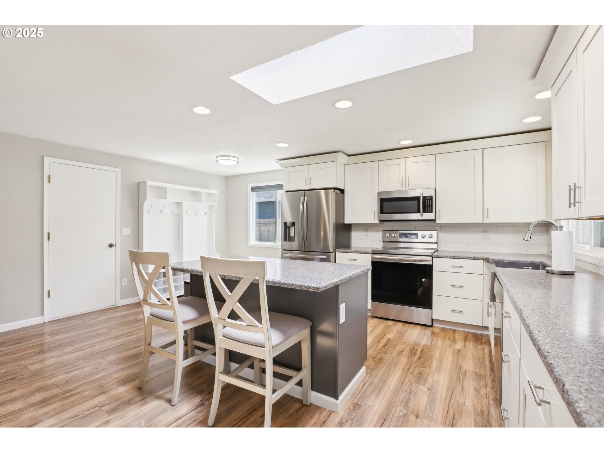 29495 Southwest Yosemite Street Wilsonville, OR 97070 - Photo 16 of 40 a open kitchen with stainless steel appliances kitchen island granite countertop a stove top oven a sink dishwasher and white cabinets with wooden floor