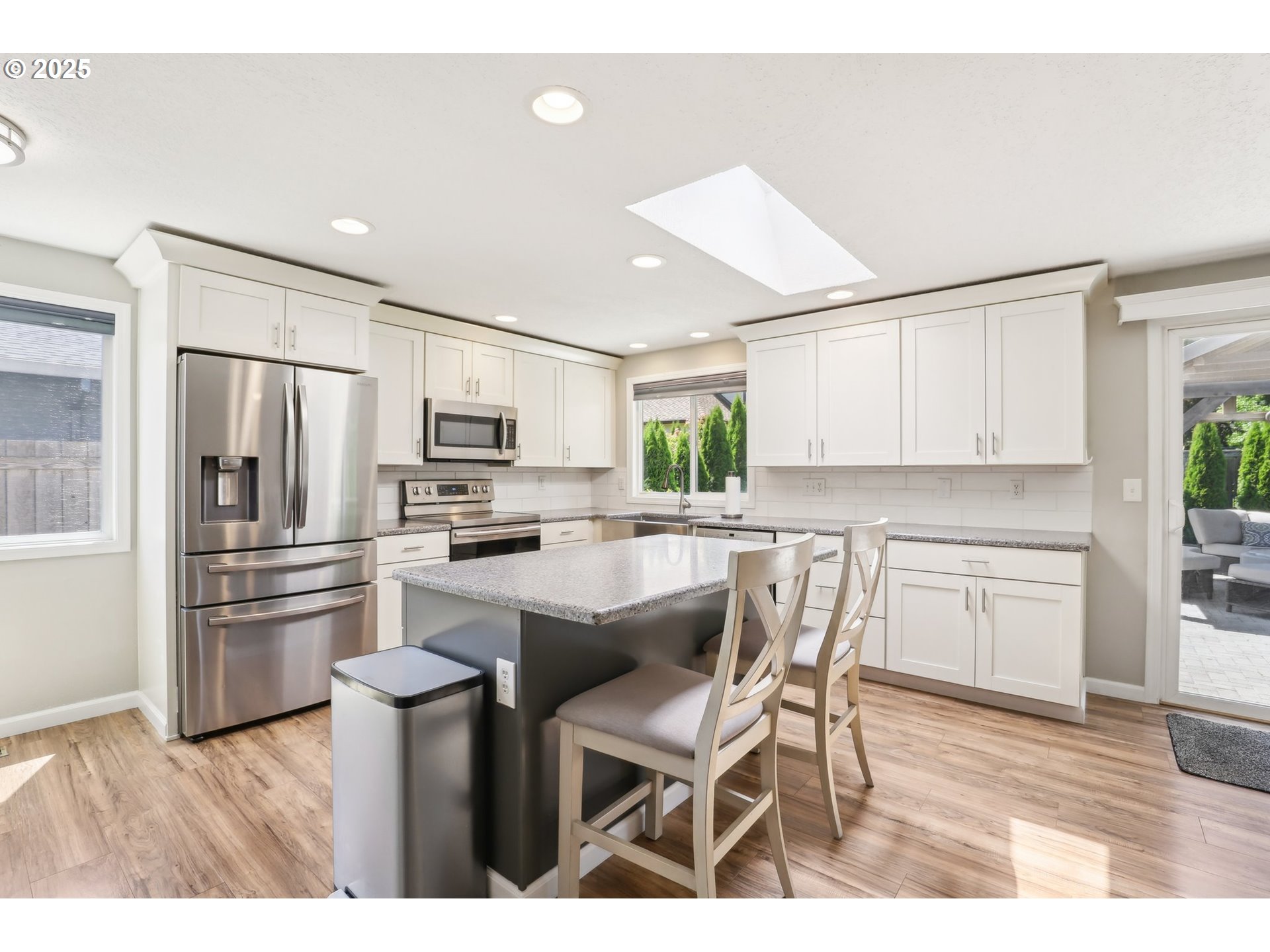 29495 Southwest Yosemite Street Wilsonville, OR 97070 - Photo 17 of 40 a kitchen with a refrigerator a microwave oven a sink dishwasher and white cabinets with wooden floor