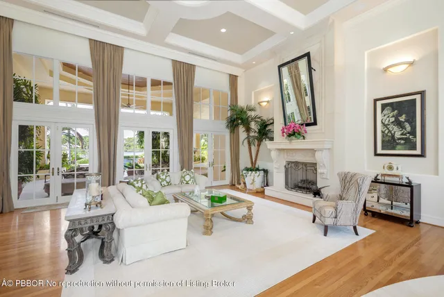a living room with furniture a fireplace and a large mirror next to a window