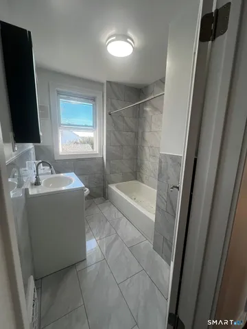 a bathroom with a bathtub sink and mirror