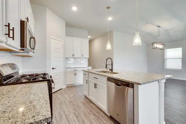 a kitchen with stainless steel appliances granite countertop a sink stove and cabinets