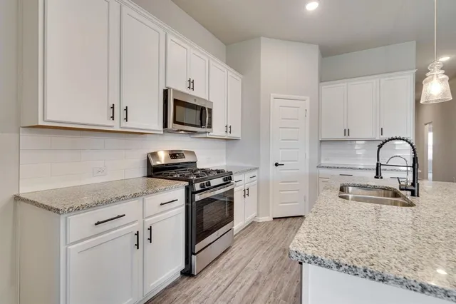 a kitchen with stainless steel appliances granite countertop white cabinets a sink and dishwasher